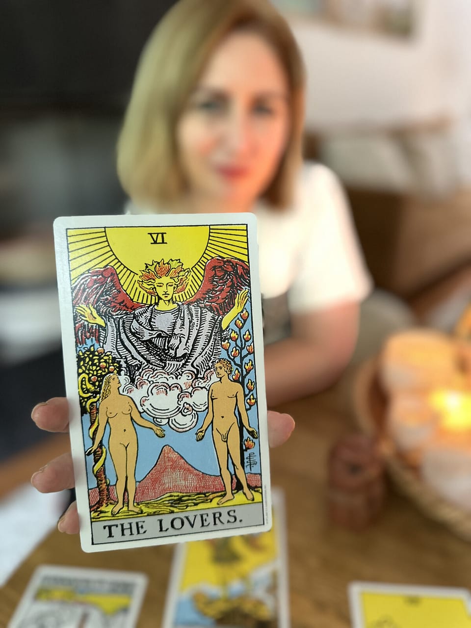Mujer sosteniendo la carta Los Enamorados frente a la cámara